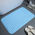 Blue textured bath mat on a bathroom floor with a sink and toiletries in the background.