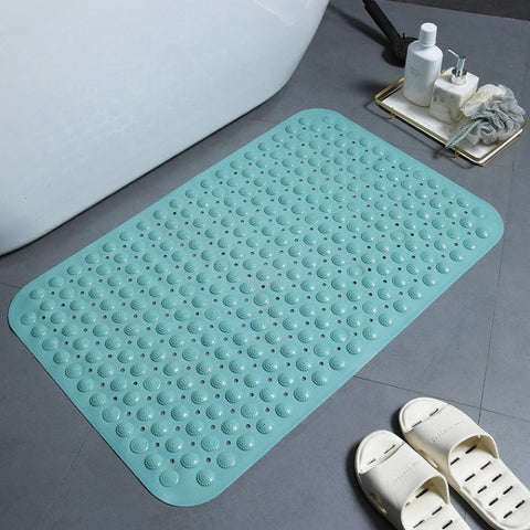 Mars Green textured bath mat on a bathroom floor with a bathtub and slippers in the background.
