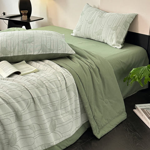 Soft green bedding with quilt and pillows styled in modern room setting