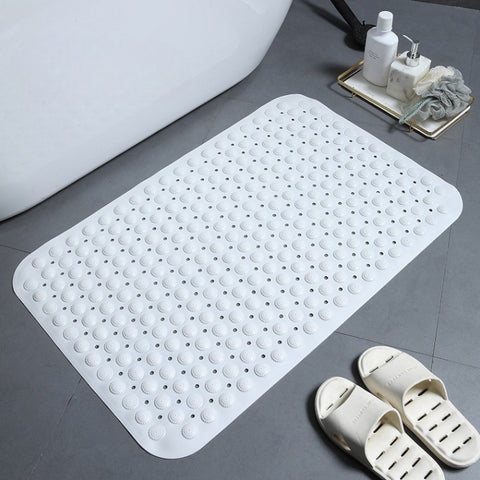 White textured bath mat on a bathroom floor with a tray of toiletries and slippers.