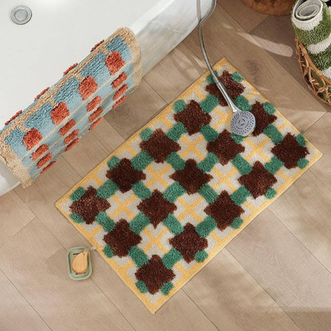 Yellow and green Moroccan-style bath mat with brown accents on wood floor