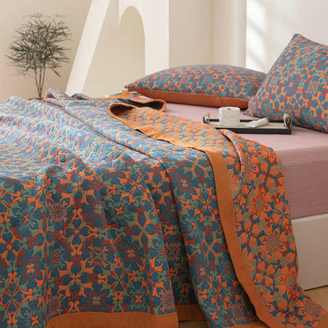 Bed with floral patterned bedding in orange and blue on a white bed frame.