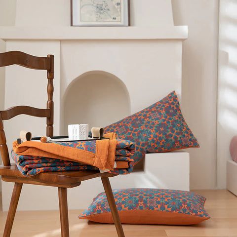 Decorative pillows and blanket on a wooden chair with a fireplace in the background