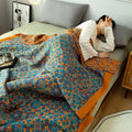 Person lying on a bed with a colorful patterned quilt, wearing a white sweater.