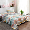Soft pastel blue and beige cotton blanket with elegant scallop pattern on bed in bright room
