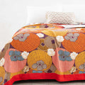 Close-up view of Persimmon Bloom cotton blanket showing vibrant floral and fruit pattern with red border on bed