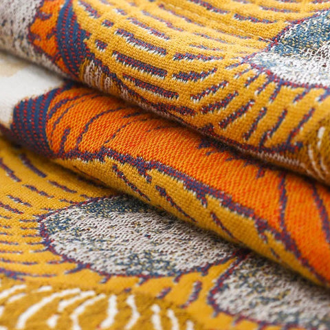 Close-up detail of Persimmon Bloom cotton pillowcases showing vibrant orange and yellow jacquard weave pattern with texture and stitching.