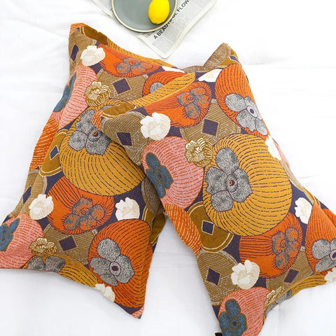 Top view of Persimmon Bloom cotton pillowcases showcasing bright orange, yellow, and gray persimmon and floral patterns on white bedding.