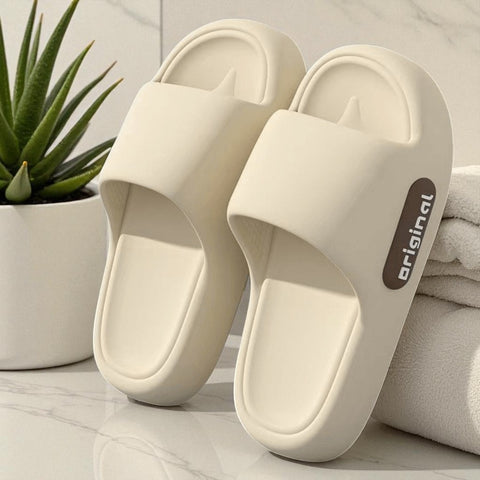 Beige slides with 'original' branding on a light surface with a plant and towel in the background