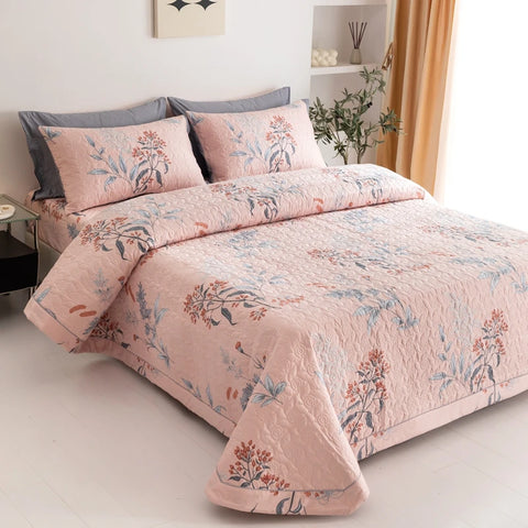 Pink botanical quilt and matching pillowcases styled in cozy bedroom setting