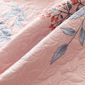Close-up of a pink quilt with floral embroidery