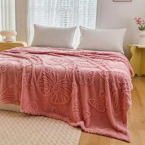 Pink butterfly textured fleece throw blanket draped across white bed in cozy room

