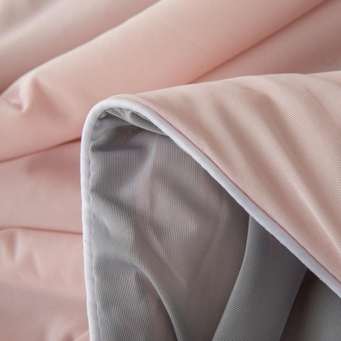 Close-up of soft pink and gray ice silk quilt fabric showing smooth texture and gentle folds.