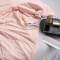 Close-up of soft pink and gray double-layered ice silk quilt draped on black side table