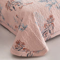 Pink quilted cotton bedding corner with floral stitching and soft texture