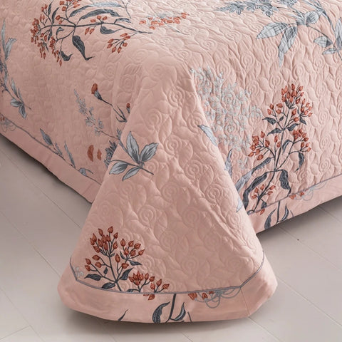 Pink quilted cotton bedding corner with floral stitching and soft texture