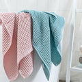 Pink and teal waffle bath towels hanging neatly side by side