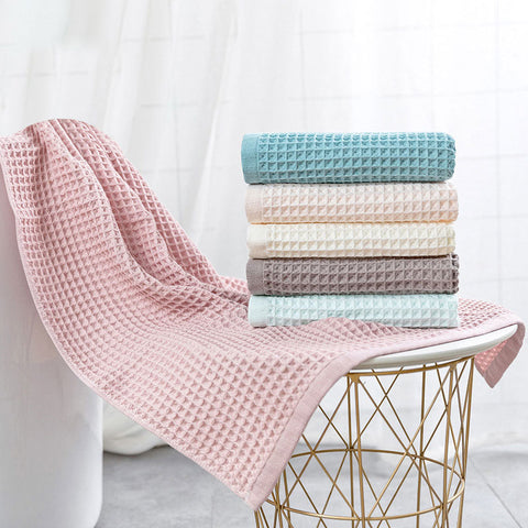 Pink and teal waffle bath towels hanging neatly side by side