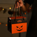 Halloween-themed treat bag with a jack-o'-lantern design held by a person.