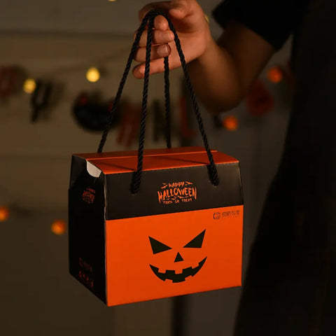 Halloween-themed treat bag with a jack-o'-lantern design held by a person.