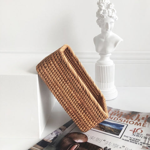 Woven brown basket on a white surface with a statue and magazine in the background