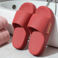 Red slides with 'original' text on a bathroom floor next to pink towels.