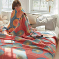 Woman wrapped in red dandelion print cotton quilt – cozy and playful bedroom scene