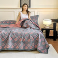 Cotton quilt with jacquard pattern in red and gray on a queen bed