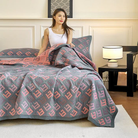 Cotton quilt with jacquard pattern in red and gray on a queen bed