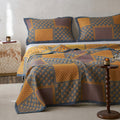Bed with a patterned quilt and pillows in a bedroom setting.