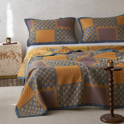 Bed with a patterned quilt and pillows in a bedroom setting.