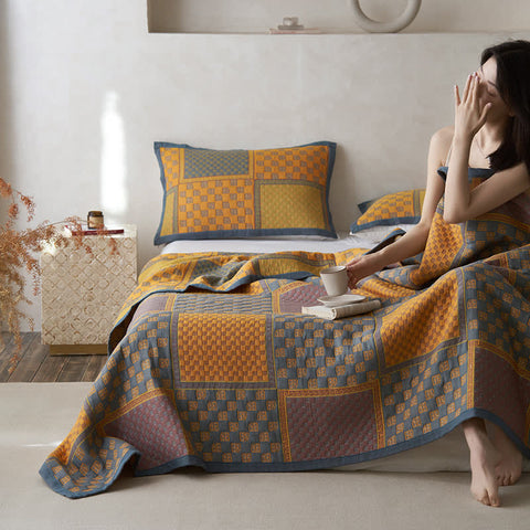 Woman reading under retro cotton patchwork blanket on bed