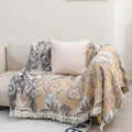 Reversible cotton couch cover blanket with tassels, beige and gray jacquard pattern draped on sofa