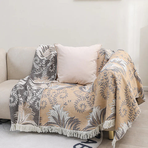 Reversible cotton couch cover blanket with tassels, beige and gray jacquard pattern draped on sofa