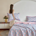 Woman holding polka dot pillows in a bedroom with matching bedding.