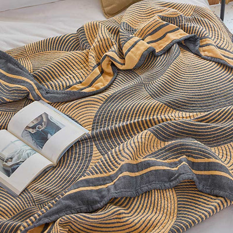 Textured blanket with wavy pattern draped over a surface, with an open book underneath.