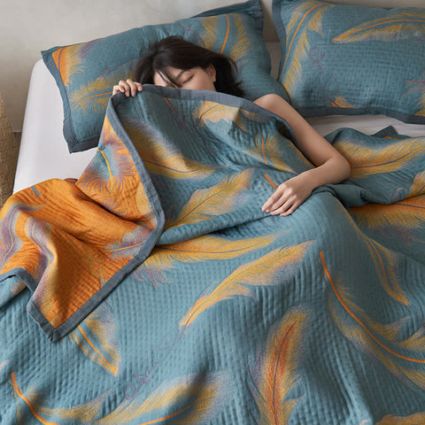 Woman resting under reversible feather cotton quilt in teal and orange