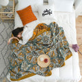 Reversible summer blanket with orange trim styled on white bed
