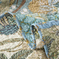 Rolled cotton quilt showcasing reversible floral stitching in green and blue tones