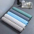 Rolled bath mats in assorted colors near bathtub