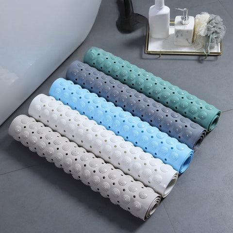 Rolled bath mats in assorted colors near bathtub