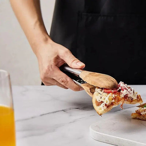 Kitchen tongs picking up salad on countertop