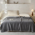 Slate gray muslin cotton blanket with white trim on minimal bedroom setup
