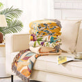 Stack of colorful patterned blankets on a beige sofa with a plant in the background