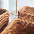 Close-up of woven wicker chairs with a white wall in the background
