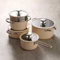 4-piece cream enamel cookware set neatly stacked on beige background