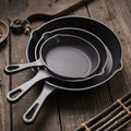 Set of black cast iron skillets on a wooden surface