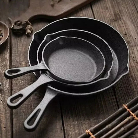 Set of black cast iron skillets on a wooden surface