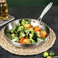 Stainless steel frying pan with vegetables on a woven mat