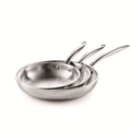 Set of three stainless steel frying pans on a white background